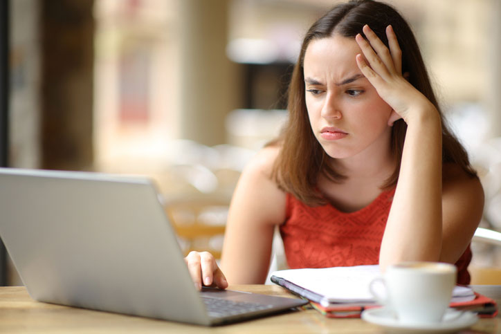 Frustrated young woman learning in cafe researching graduate certificate programs representing challenges and determination in pursuing addiction counseling credentials for licensed mental health professionals