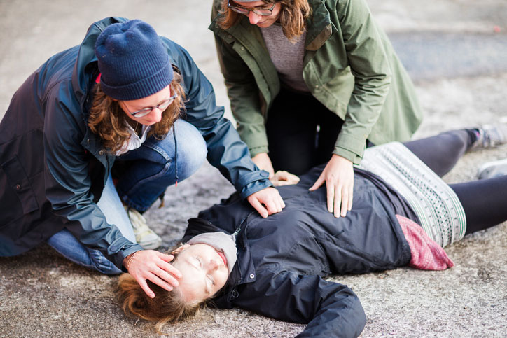 two women looking after passed out woman