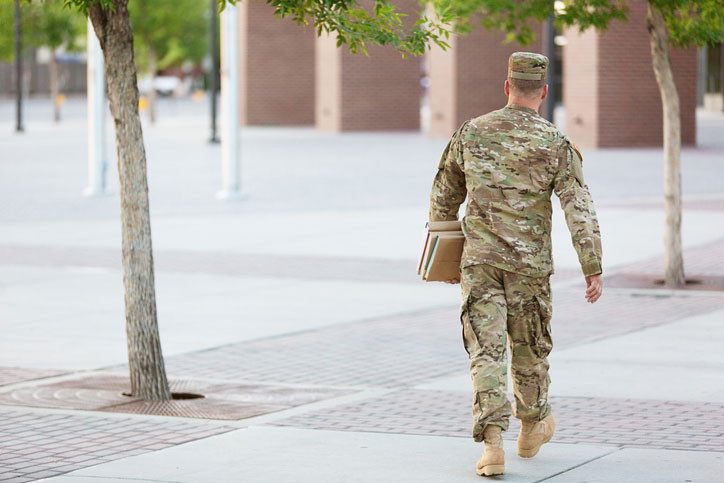 soldier carrying books on campus