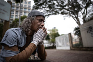 homeless man sitting on sidewalk