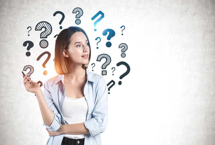 Young woman contemplating education choices with question marks surrounding her, representing the decision between associates vs bachelor's degree in substance abuse counseling